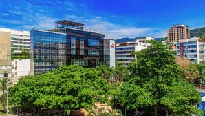 Un bâtiment moderne à la façade vitrée, entouré d’arbres verdoyants.