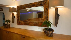 A wooden counter with a large mirror, two wall-mounted lamps, and two potted plants. - Pension Milan (Zell am See)