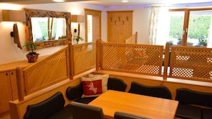 A dining area with wooden furniture, a table, and chairs. There is a wooden partition with a lattice design. - Pension Milan (Zell am See)