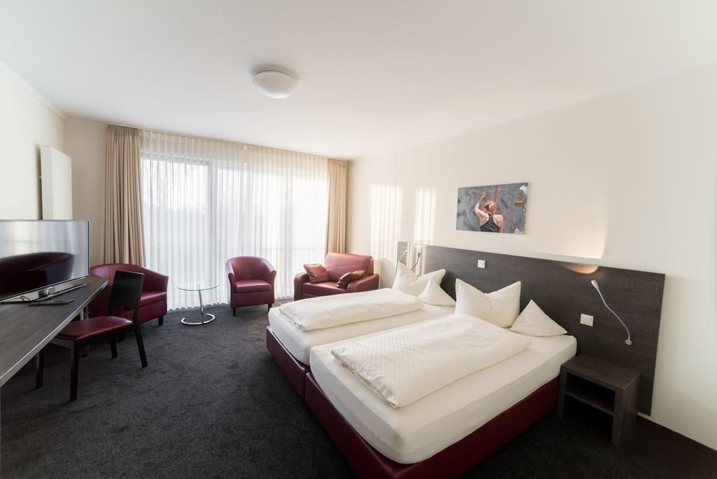 Una habitación de hotel con una cama, dos sillas, un escritorio y un televisor.