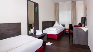 Habitación de hotel con dos camas, un escritorio, una silla, un espejo y una ventana con cortinas.