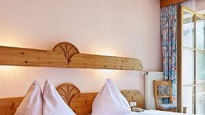 A double bed with a wooden headboard, two pillows, and a bedside table with a lamp. - Schwaiger Hotel (EBEN)