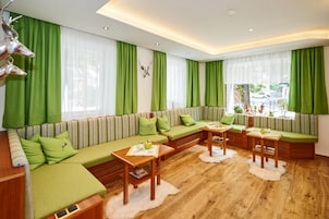 Un salón moderno con un sofá verde, mesas de madera y vista a la calle.
