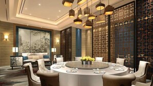 A modern dining area with a round table, multiple chairs, and hanging pendant lights. - Grand NEW Century Hotel Fuyang (Hangzhou)