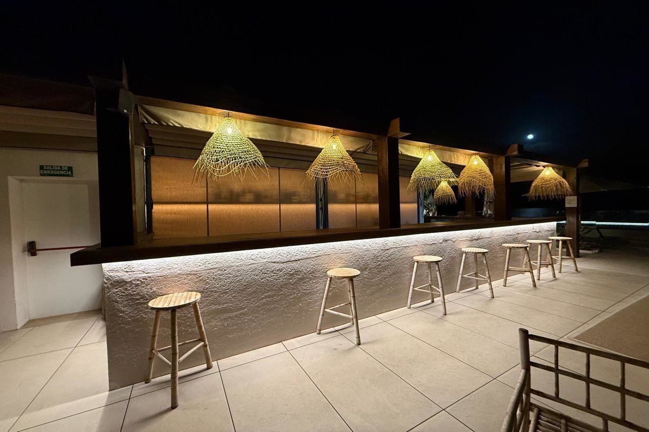 A bar area with stools and hanging lights.