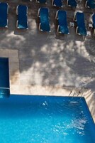 Una piscina con sillas de descanso y una zona sombreada.