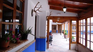 A corridor with wooden beams, potted plants, and a bench. - Hotel El Cortijo de Daimiel (Daimiel)