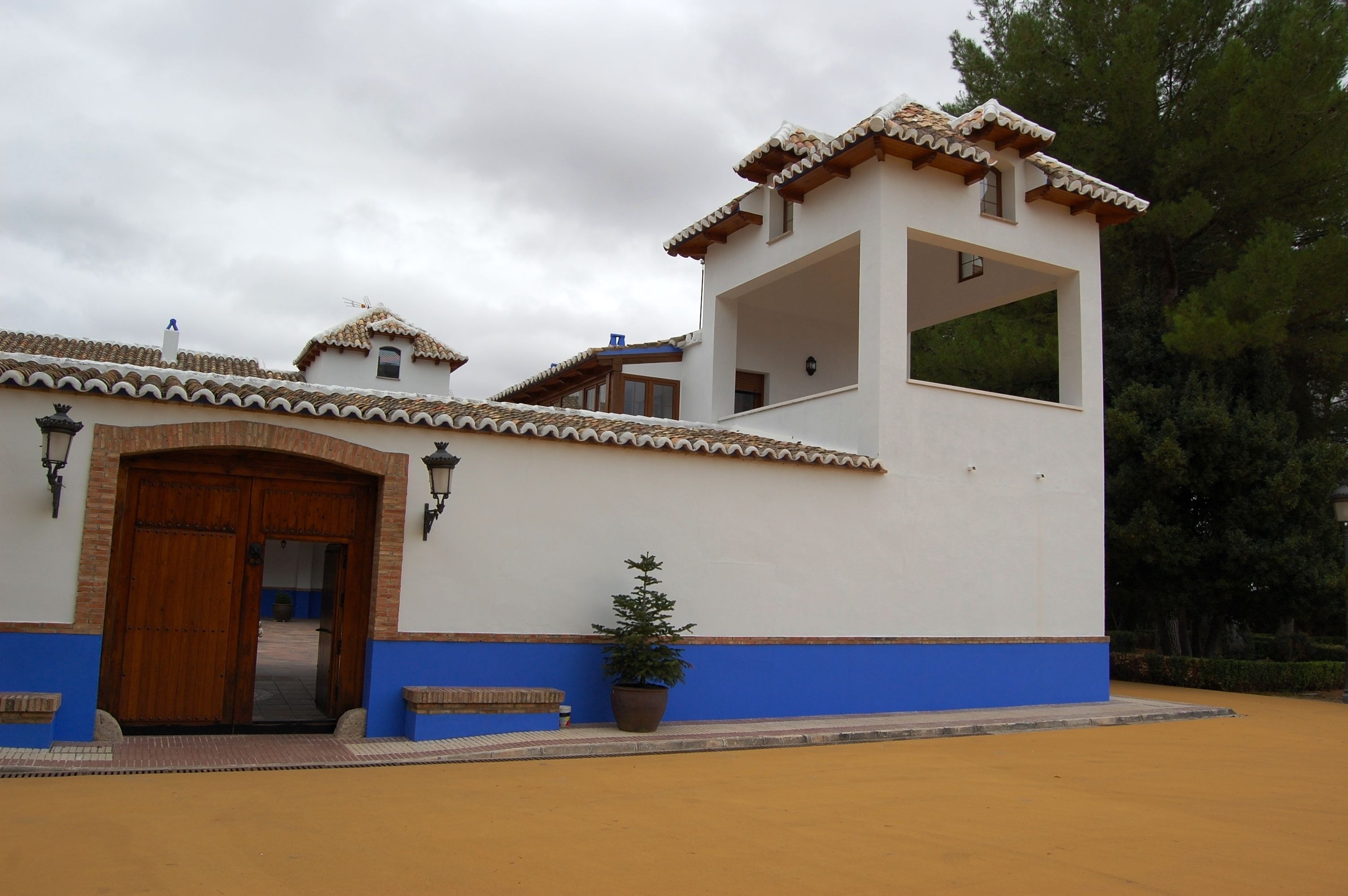 A building with a white facade, blue lower section, and terracotta roof tiles.