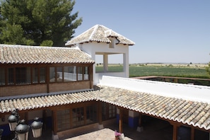 Il s’agit d’un bâtiment traditionnel, avec des toits en tuiles et des fenêtres en bois, doté d’un patio couvert et offrant une vue sur la campagne.