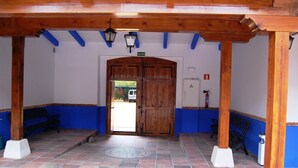 A covered entrance with a wooden door, blue walls, and tiled flooring. - Hotel El Cortijo de Daimiel (Daimiel)