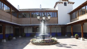 A courtyard with a central fountain, surrounded by potted plants and a tiled floor. - Hotel El Cortijo de Daimiel (Daimiel)