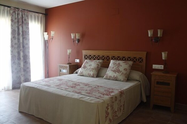 Un dormitorio con cama, dos mesitas de noche y lámparas de pared.