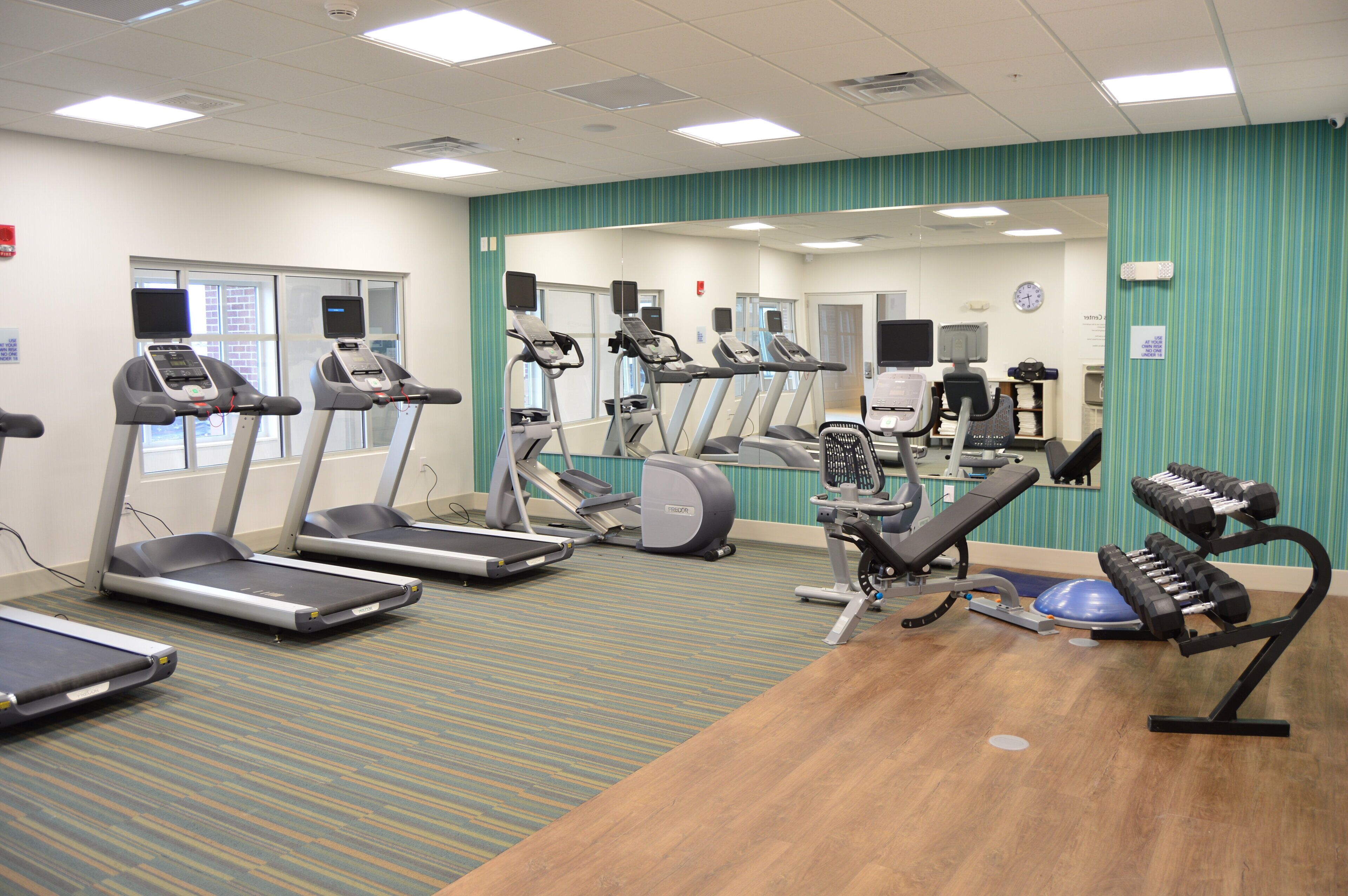 Une salle de sport équipée de tapis de course, de vélos elliptiques et de poids libres.
