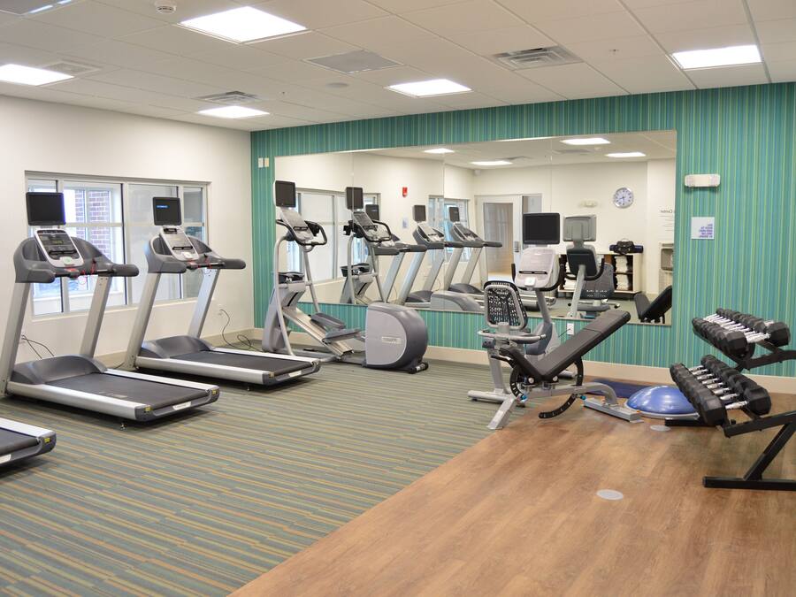 A gym with treadmills, elliptical machines, and free weights.