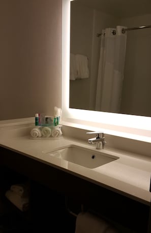A bathroom with a large mirror, a sink, and toiletries on the counter. - Holiday Inn Express & Suites Toledo West by IHG (Toledo)