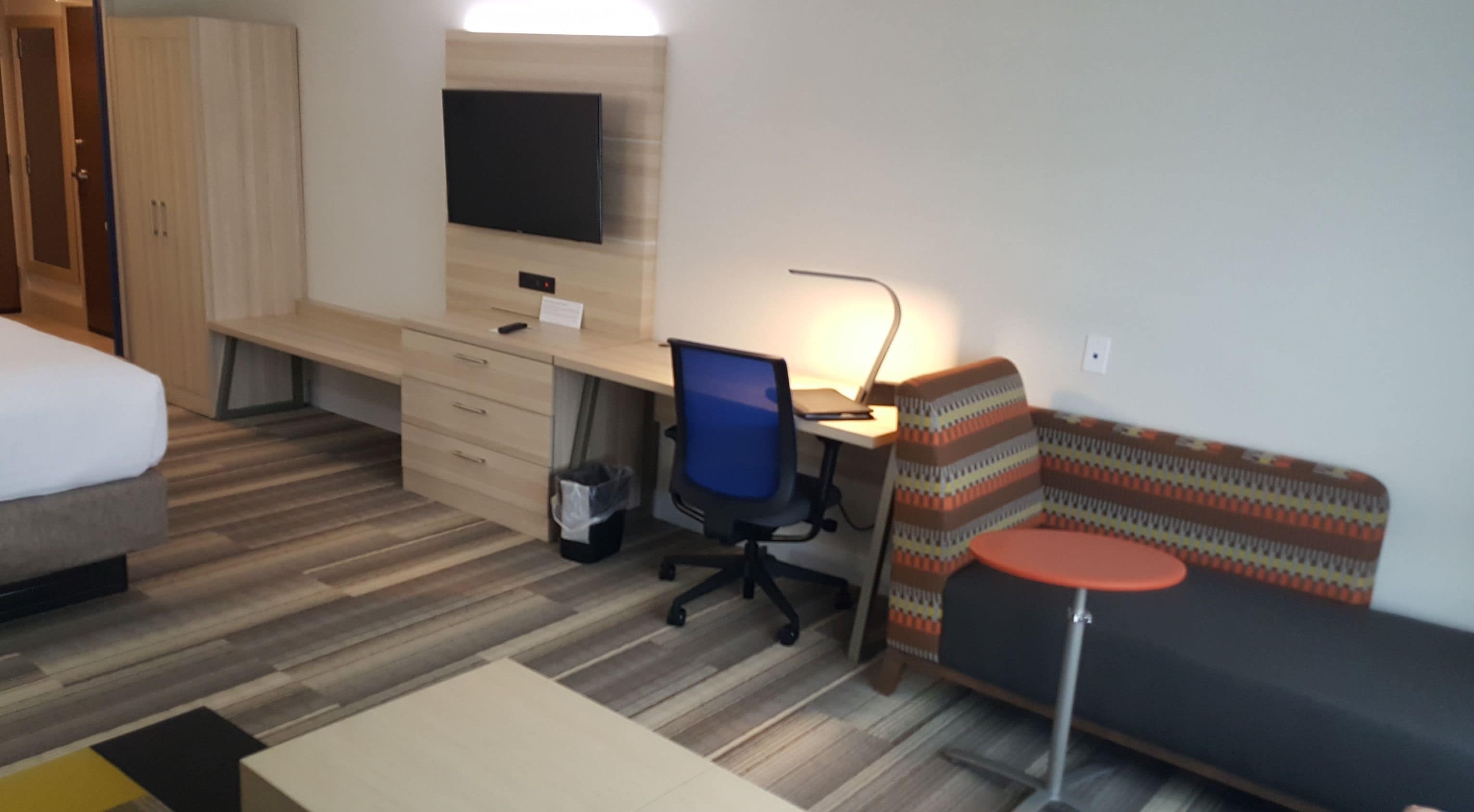 Una habitación de hotel con una cama, un escritorio, una silla, un sofá y un televisor.