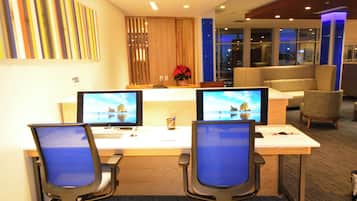 A reception desk with two monitors, a laptop, and a vase with red flowers.