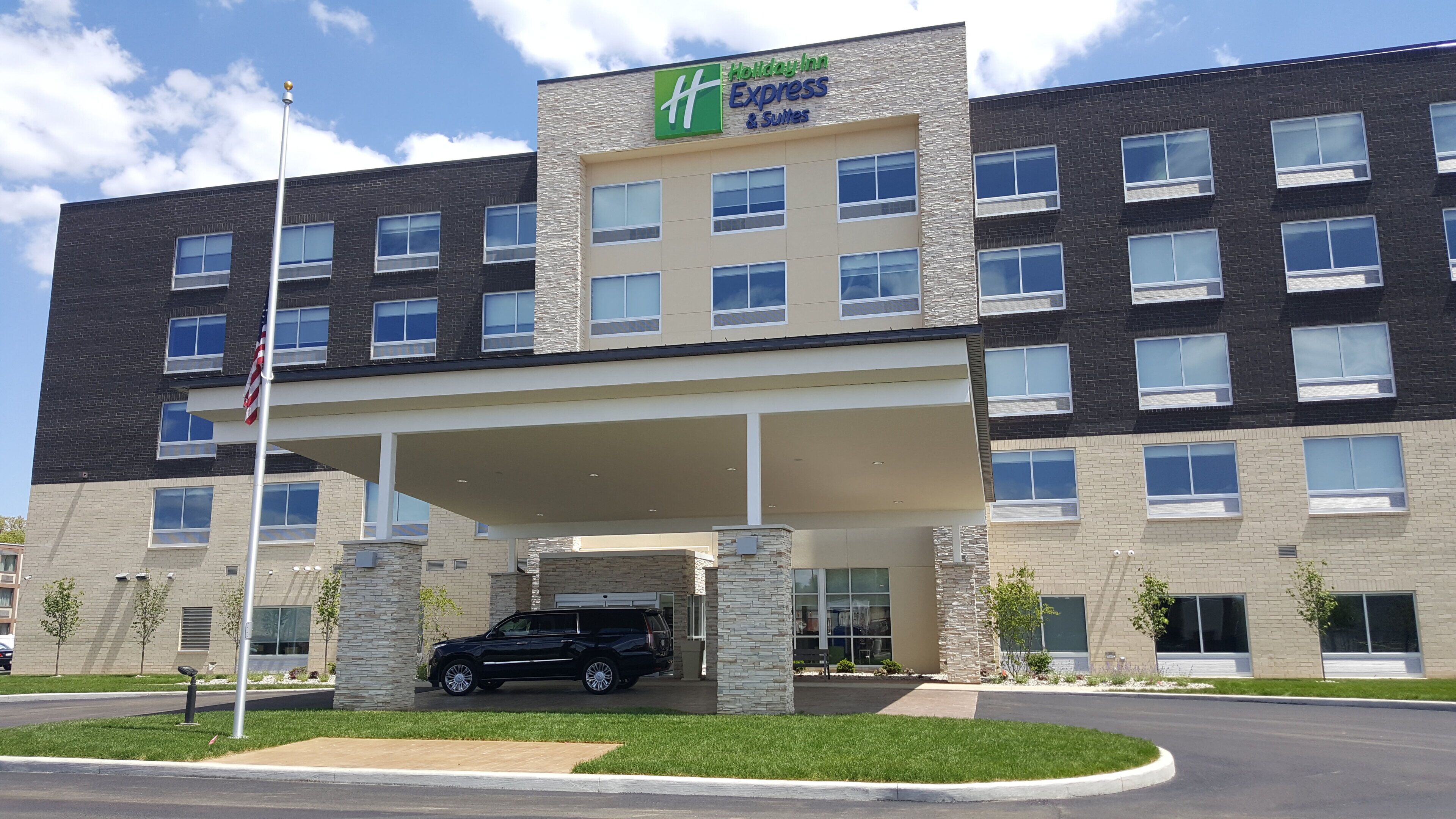 A Holiday Inn Express building with a covered entrance, multiple windows, and a flagpole.