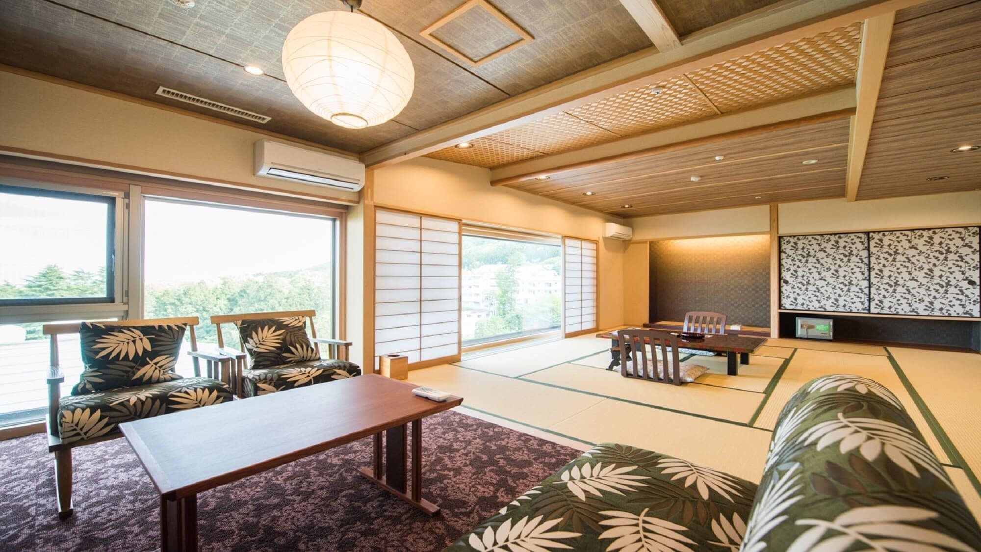 A traditional Japanese room with tatami flooring, a low table, chairs, a sofa, and a sliding door.