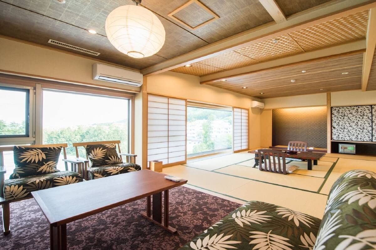 A traditional Japanese room with tatami flooring, a low table, chairs, a sofa, and a sliding door.