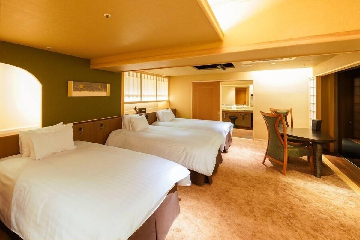 A hotel room with two beds, a dining table, and a mirror.