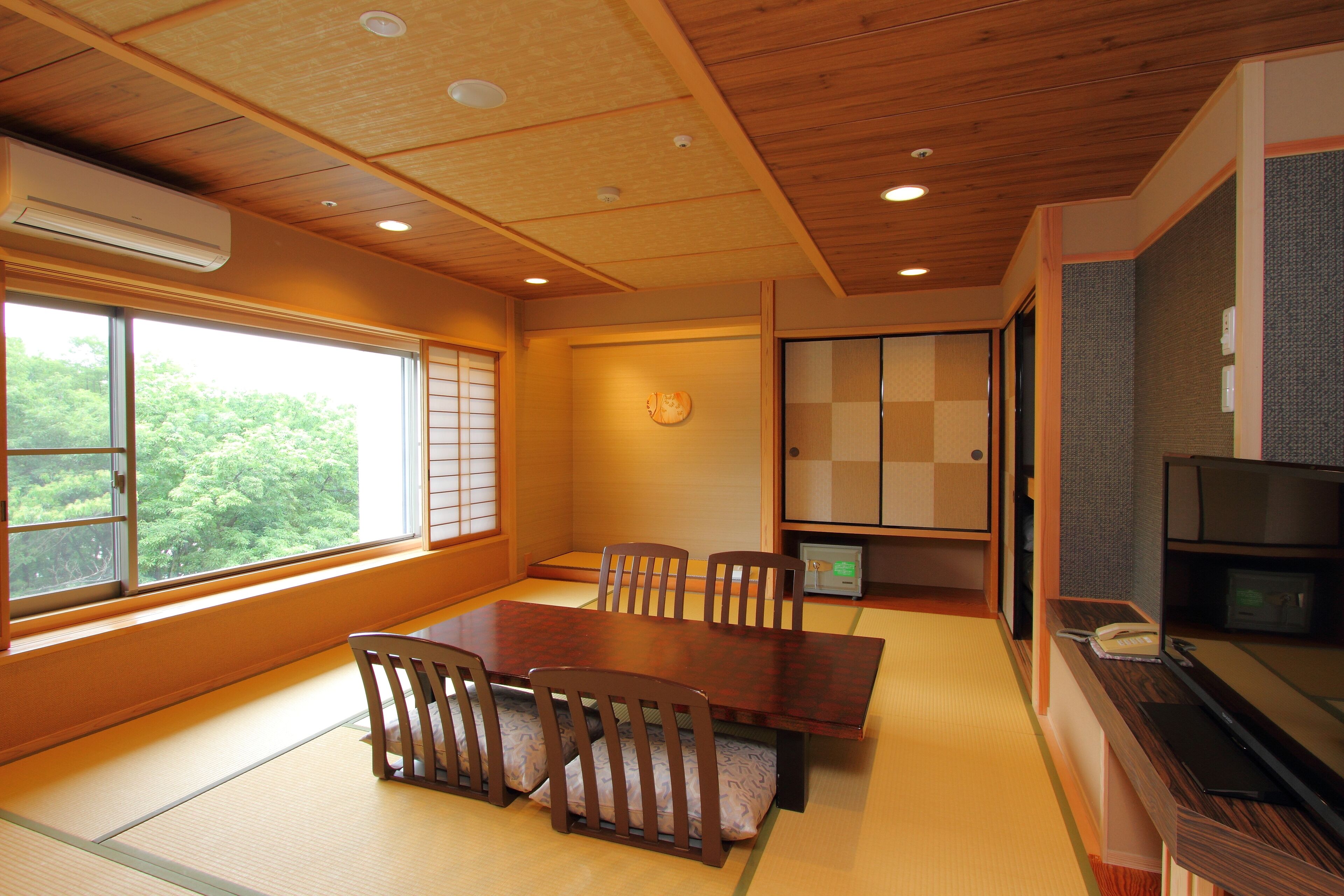 A traditional Japanese-style room with tatami flooring, a wooden dining table with chairs, a television, and a sliding door.