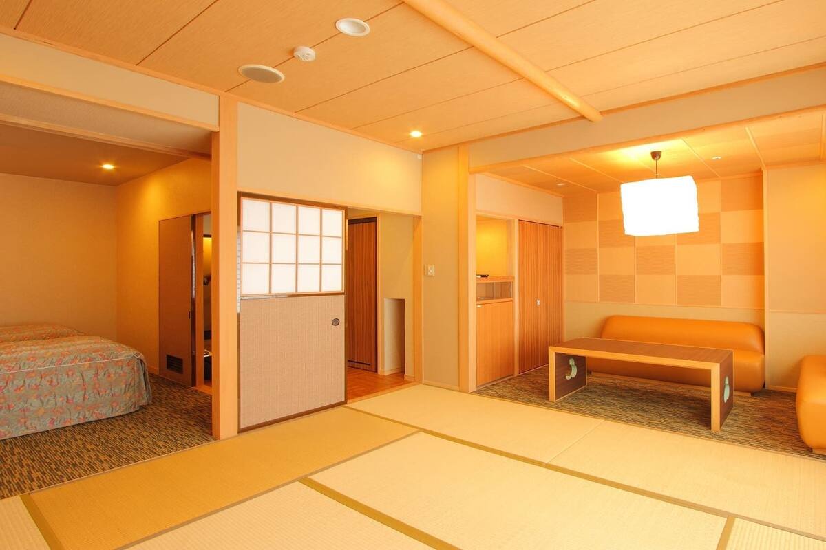 A traditional Japanese-style room with tatami flooring, a low wooden table, a cushioned bench, and sliding doors.