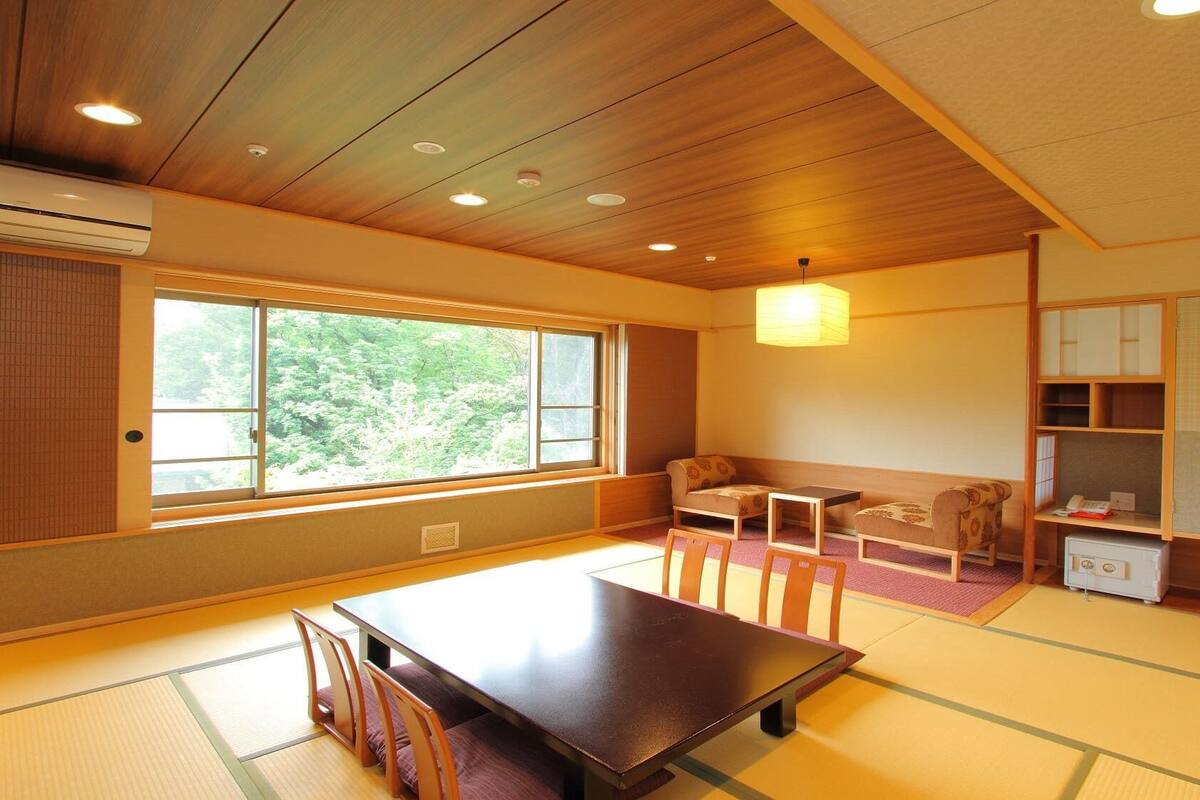 A traditional Japanese room with tatami flooring, a low table, chairs, a sofa, and a cabinet.
