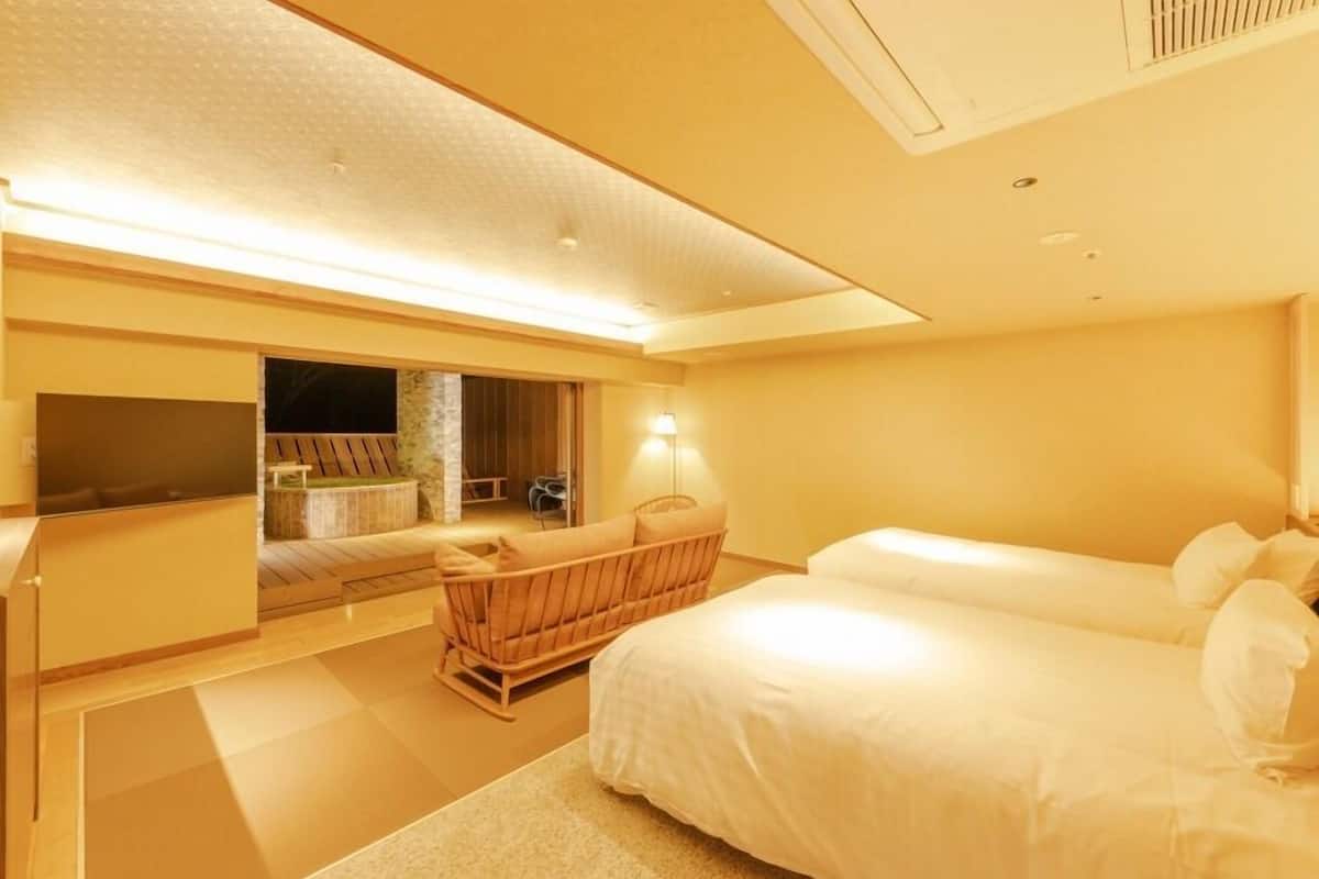 A hotel room with a bed, a seating area with a chair, a television, and a small table.