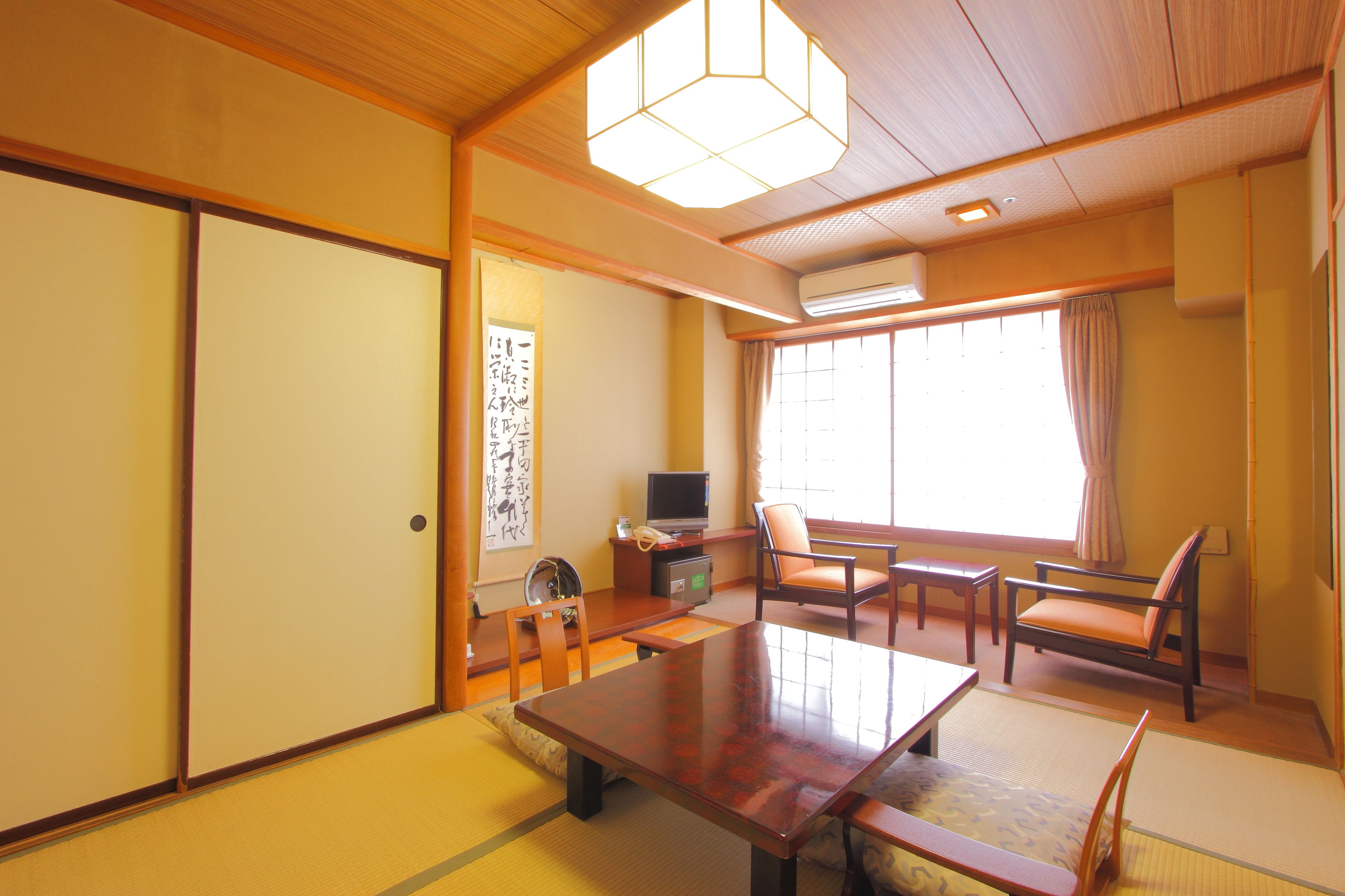 A traditional Japanese room with tatami flooring, a wooden table, and chairs.
