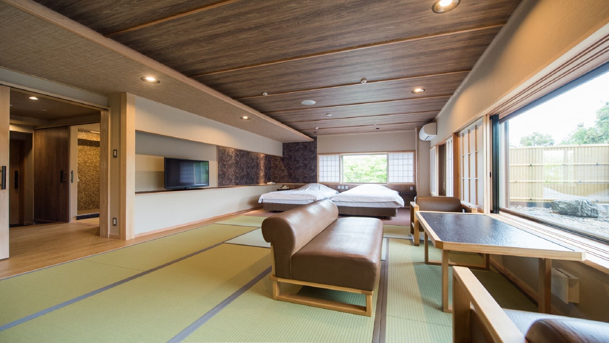 A traditional Japanese-style room with tatami flooring, a low wooden ceiling, and sliding doors.