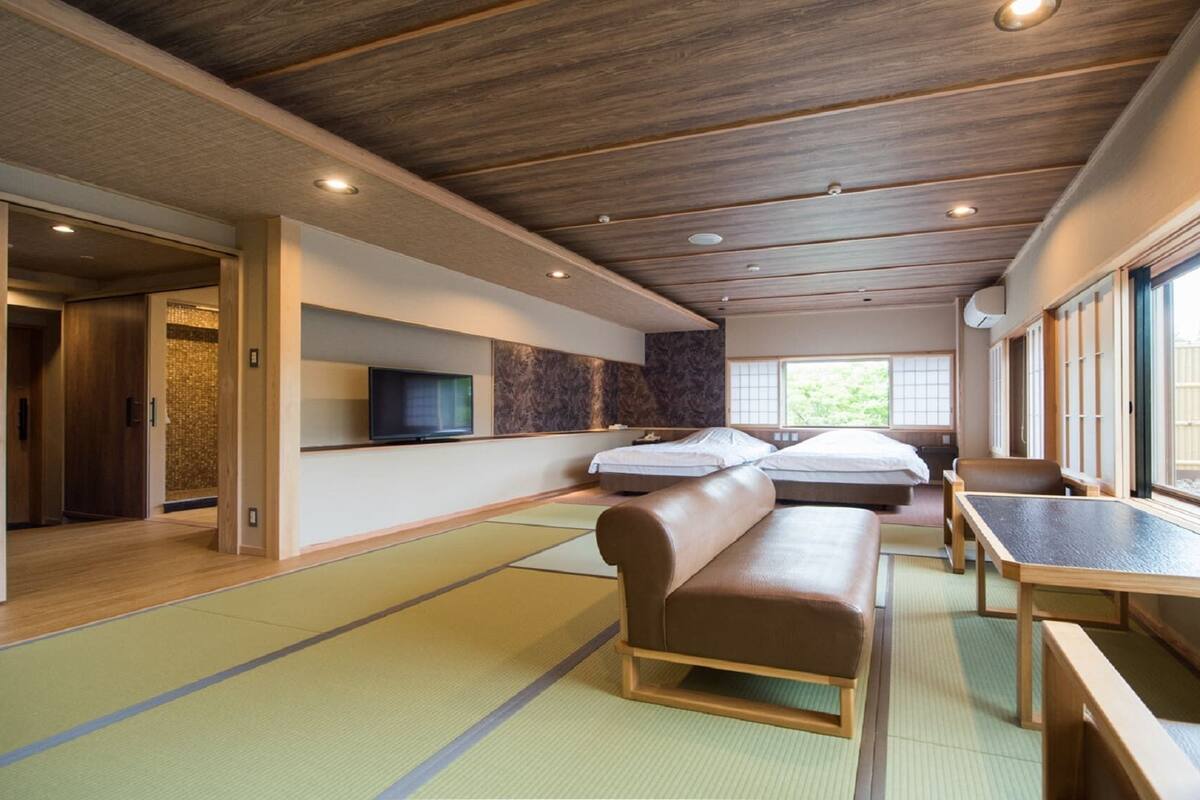 A traditional Japanese-style room with tatami flooring, a low wooden ceiling, and sliding doors.