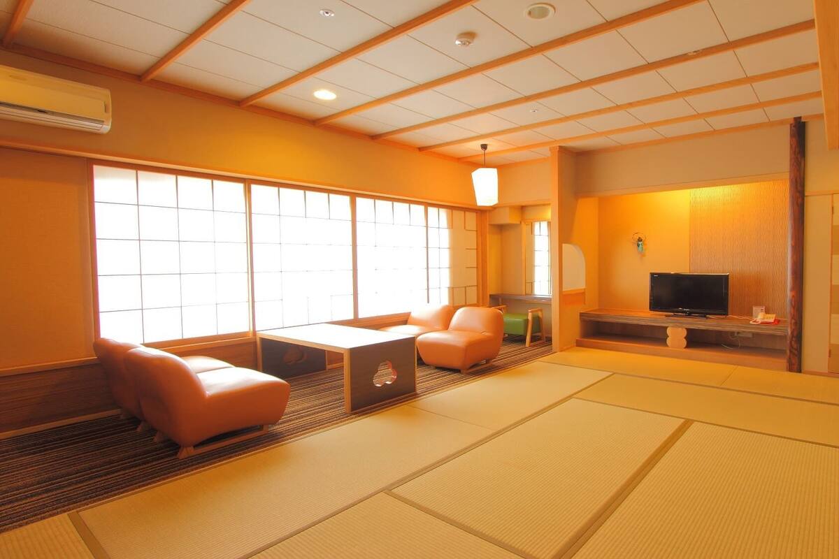 A traditional Japanese-style room with tatami flooring, a television, and sliding doors.
