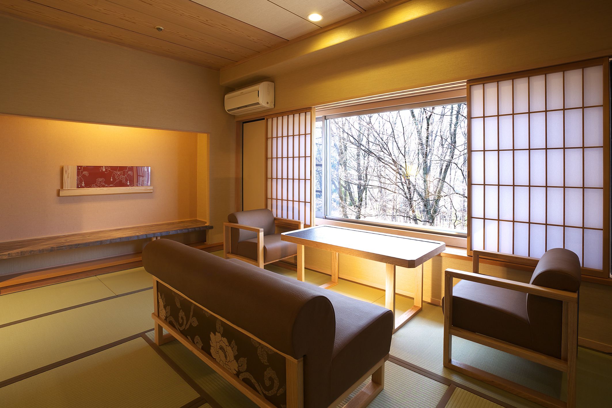 A traditional Japanese room with tatami flooring, a low table, and seating.