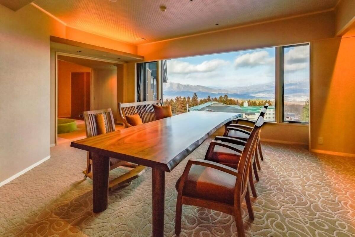 A conference room with a long table, chairs, and large windows offering a mountain view.