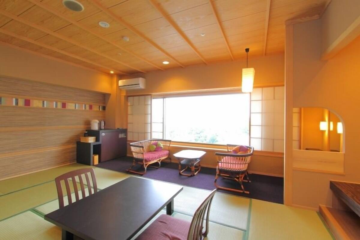 A traditional Japanese-style room with tatami flooring, low tables, and cushioned seating.