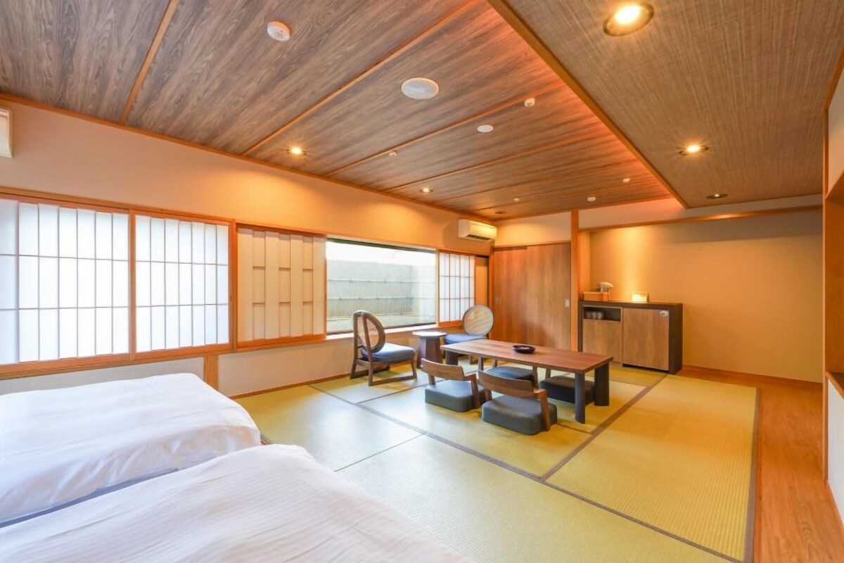 A traditional Japanese-style room with tatami flooring, a low table with cushions, and a sliding door.