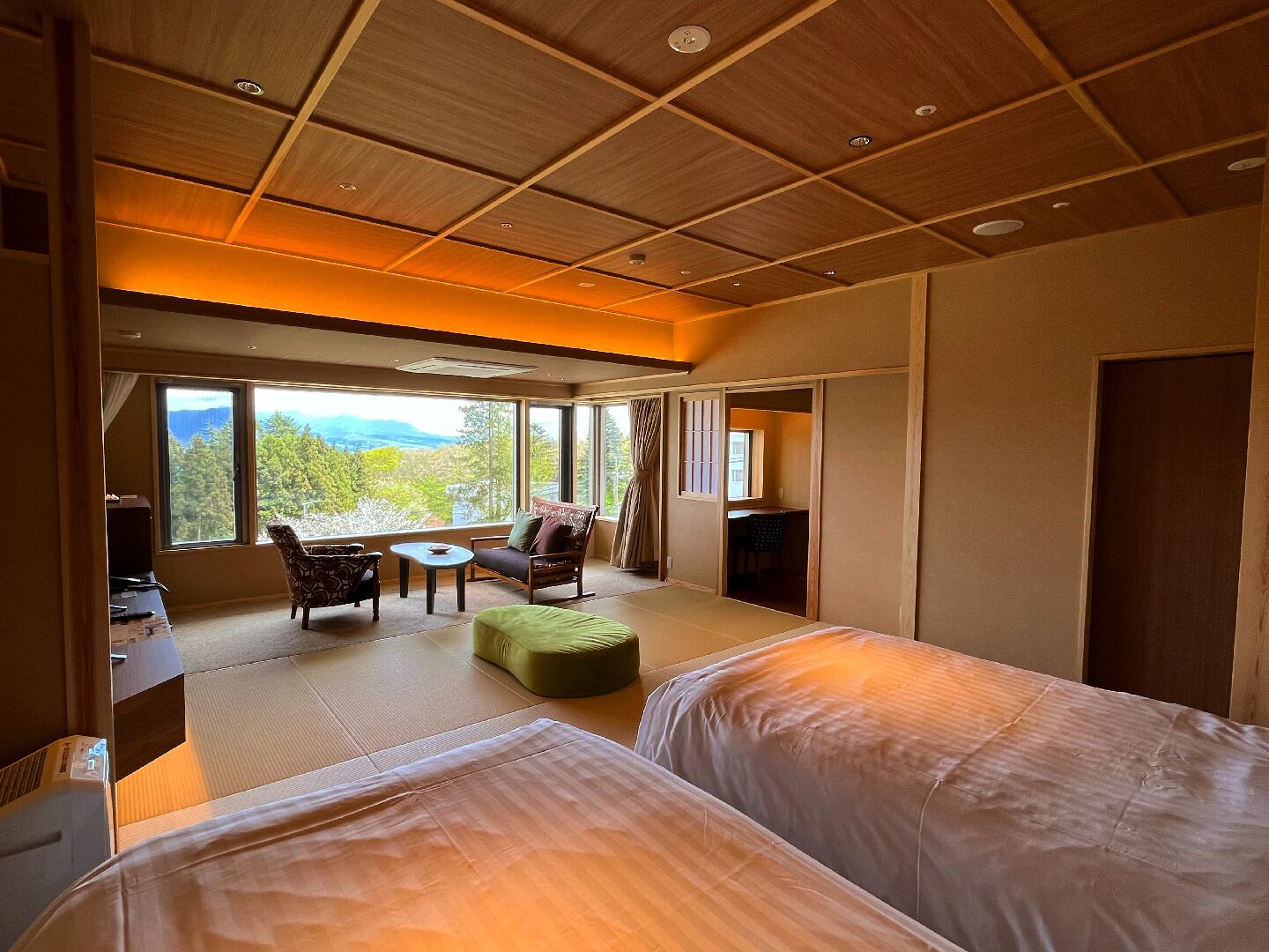 A hotel room with two beds, a sofa, a small table, and a TV.