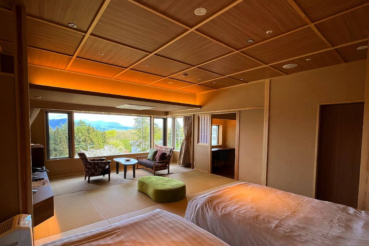 A hotel room with two beds, a sofa, a small table, and a TV.