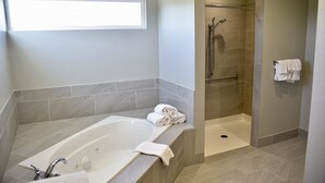 A modern bathroom with a large bathtub, a walk-in shower, and a window providing natural light. - Holiday Inn Windsor Wine Country by IHG (Windsor)