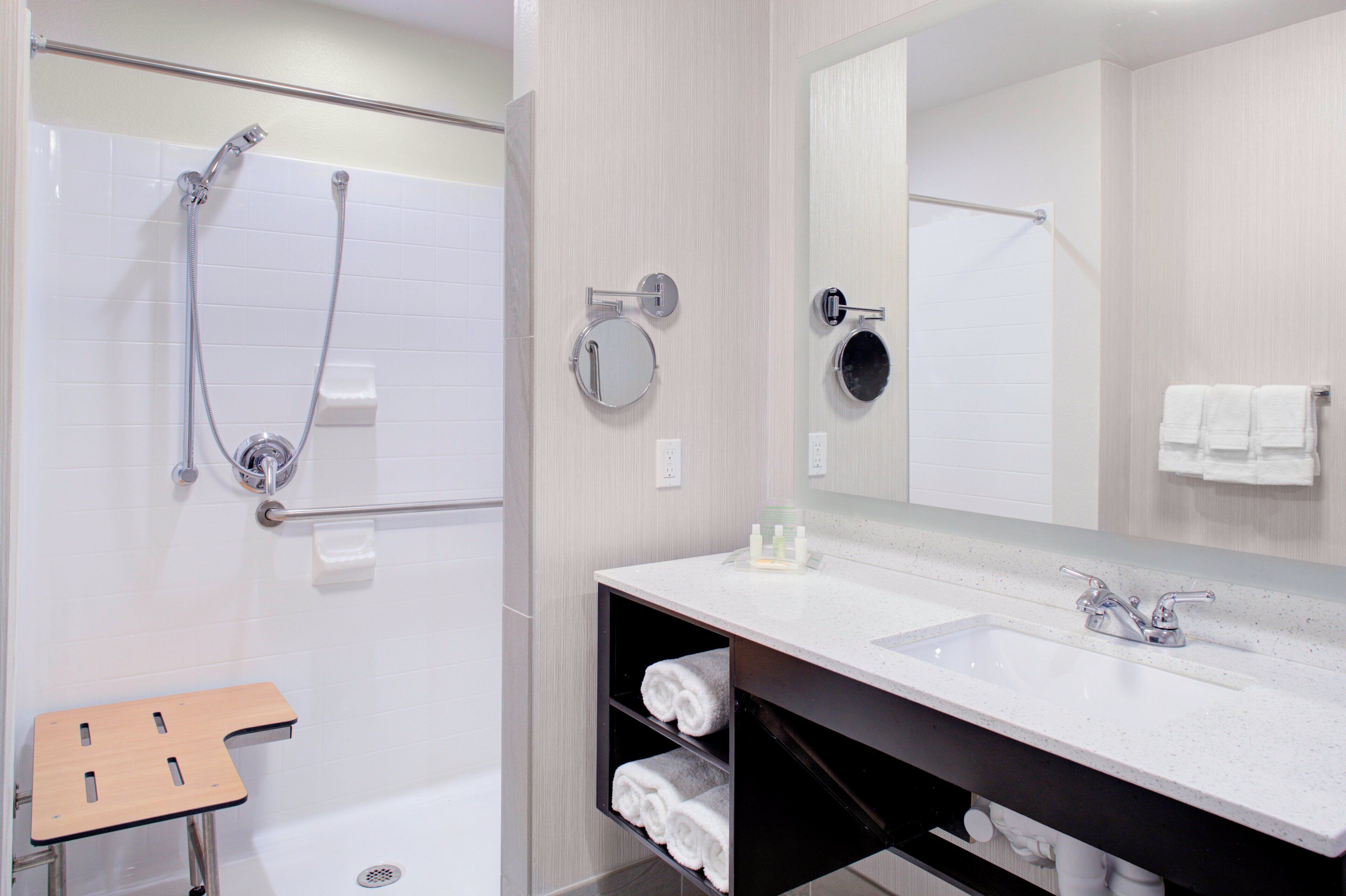 A modern bathroom with a shower, a sink, a mirror, and a towel rack.