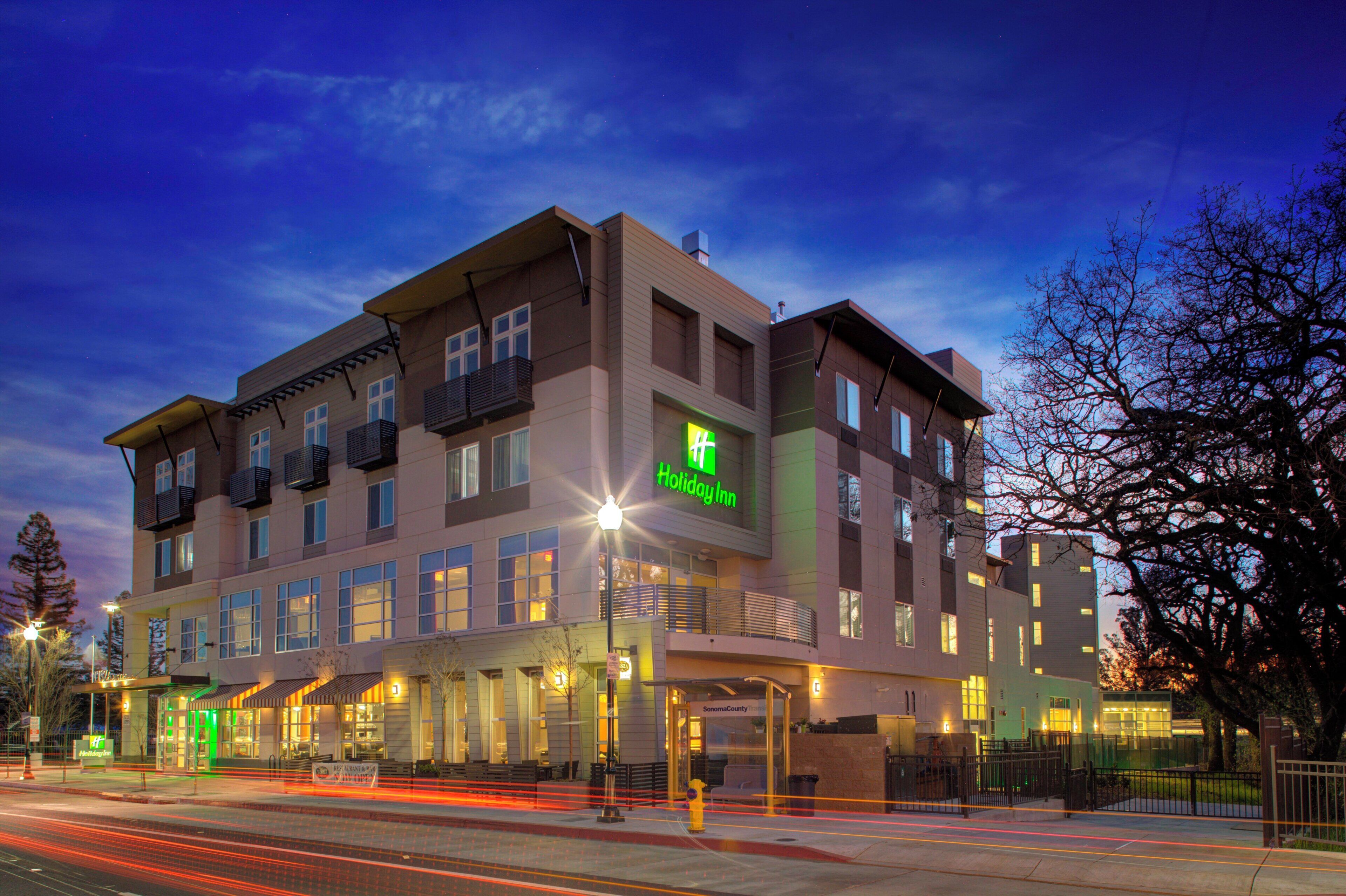 A multi-story hotel with a Holiday Inn sign, a restaurant, and a parking area.