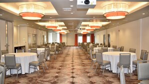 A conference room with multiple tables and chairs, a carpeted floor, and ceiling-mounted lighting fixtures. - Holiday Inn Windsor Wine Country by IHG (Windsor)