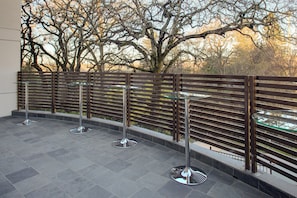 A balcony with a metal railing, a glass table, and a metal chair.