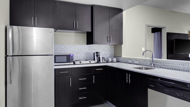 A modern kitchen with dark cabinets, stainless steel appliances, a microwave, and a dishwasher. - Holiday Inn Windsor Wine Country by IHG (Windsor)