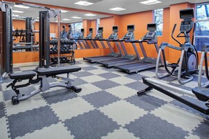 Un gimnasio con cintas de correr, máquinas de pesas y un espejo grande.