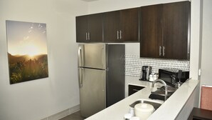 A modern kitchen with dark wooden cabinets, stainless steel appliances, and a white countertop. - Holiday Inn Windsor Wine Country by IHG (Windsor)