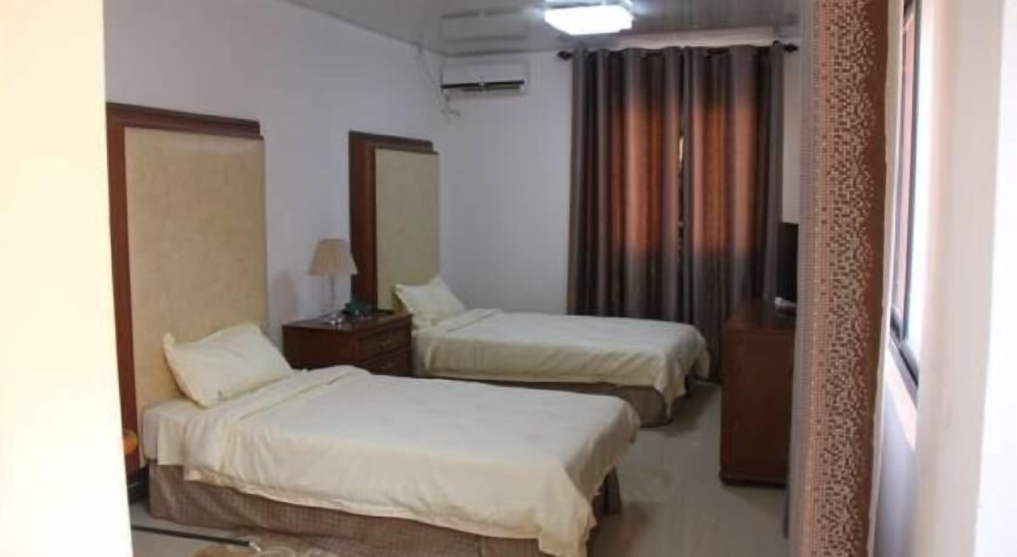 Une chambre d’hôtel avec deux lits, une commode, un miroir et un téléviseur.