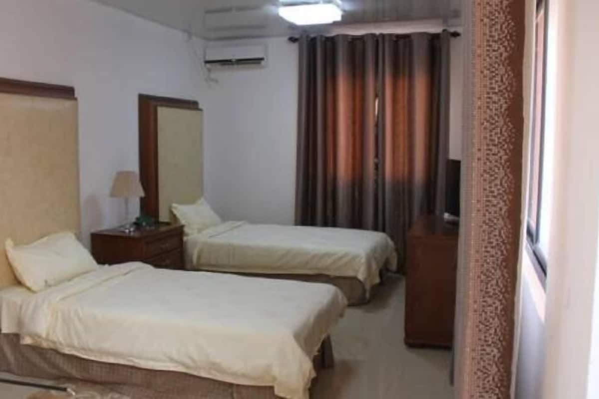 Une chambre d’hôtel avec deux lits, une commode, un miroir et un téléviseur.
