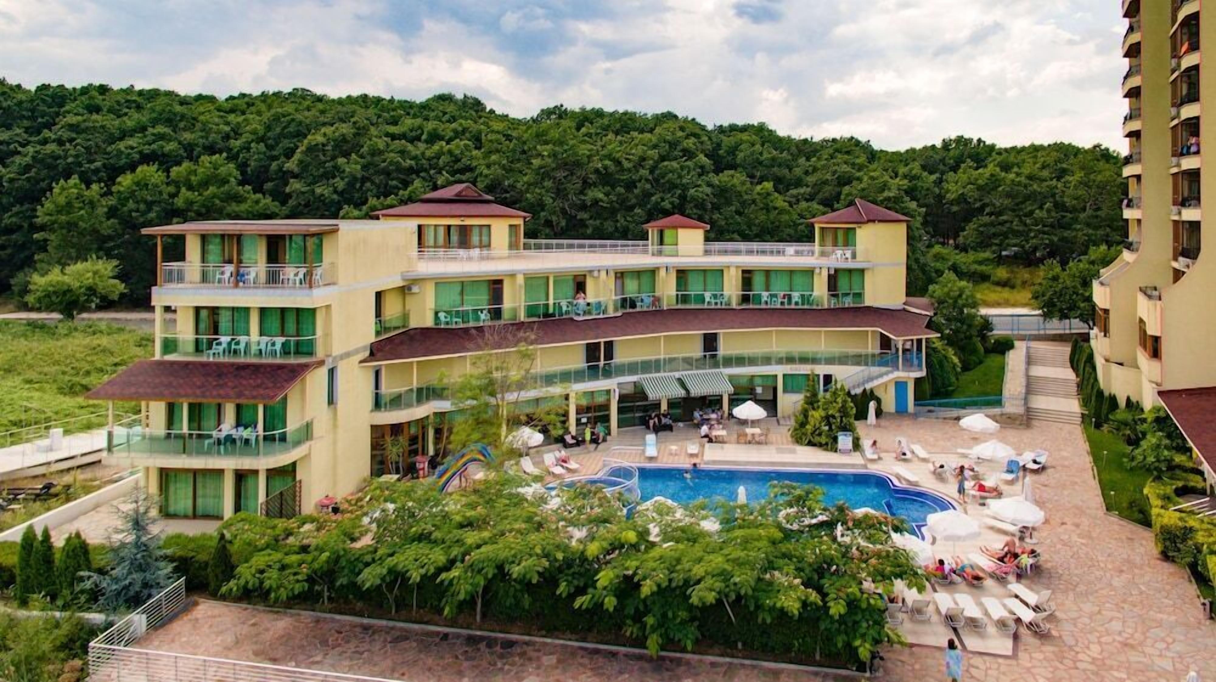Un hôtel à plusieurs étages doté d’une piscine, d’un espace extérieur aménagé et surplombant un paysage verdoyant.